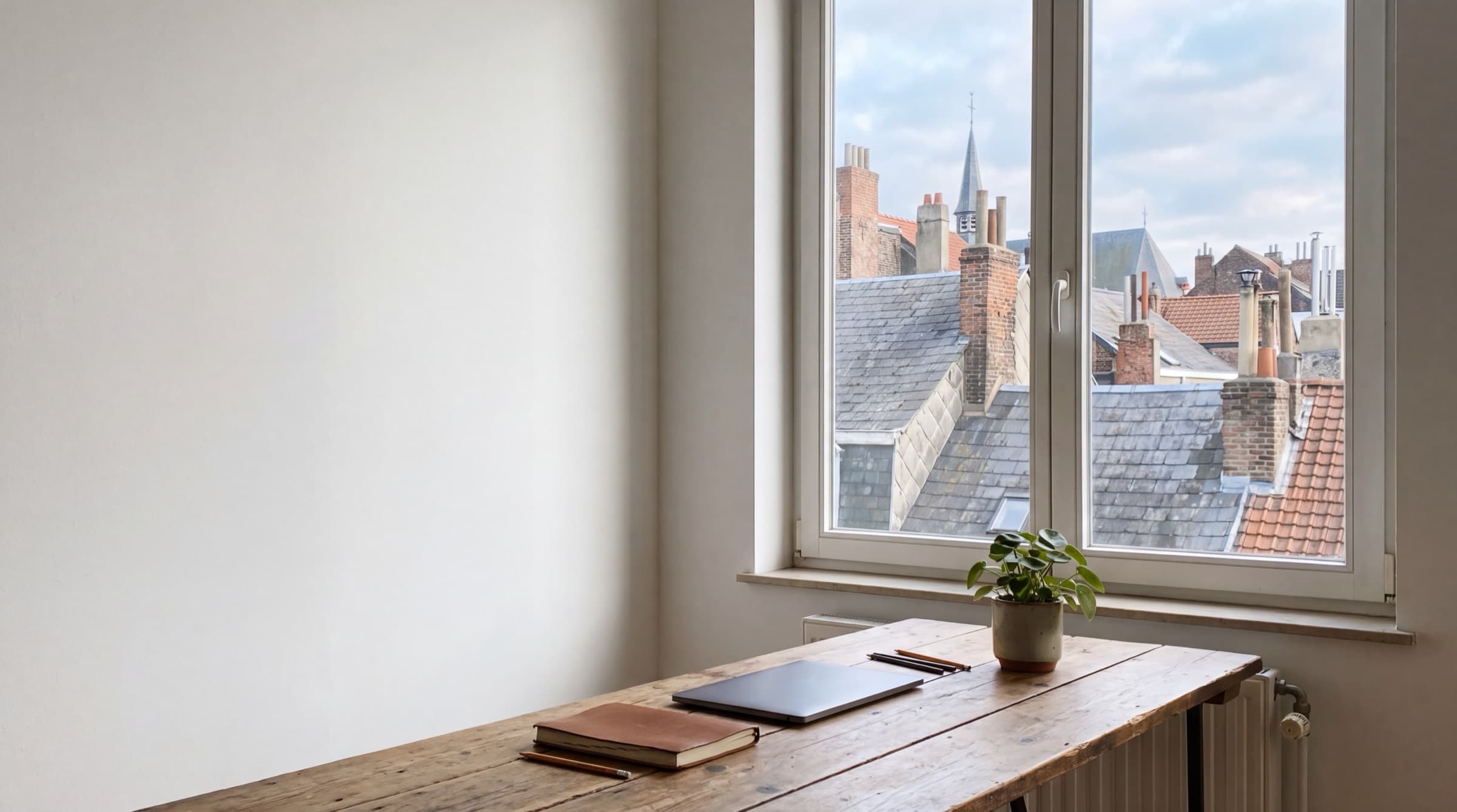 Bureau lumineux d'un studio à Bruxelles, les toits visibles par la fenêtre