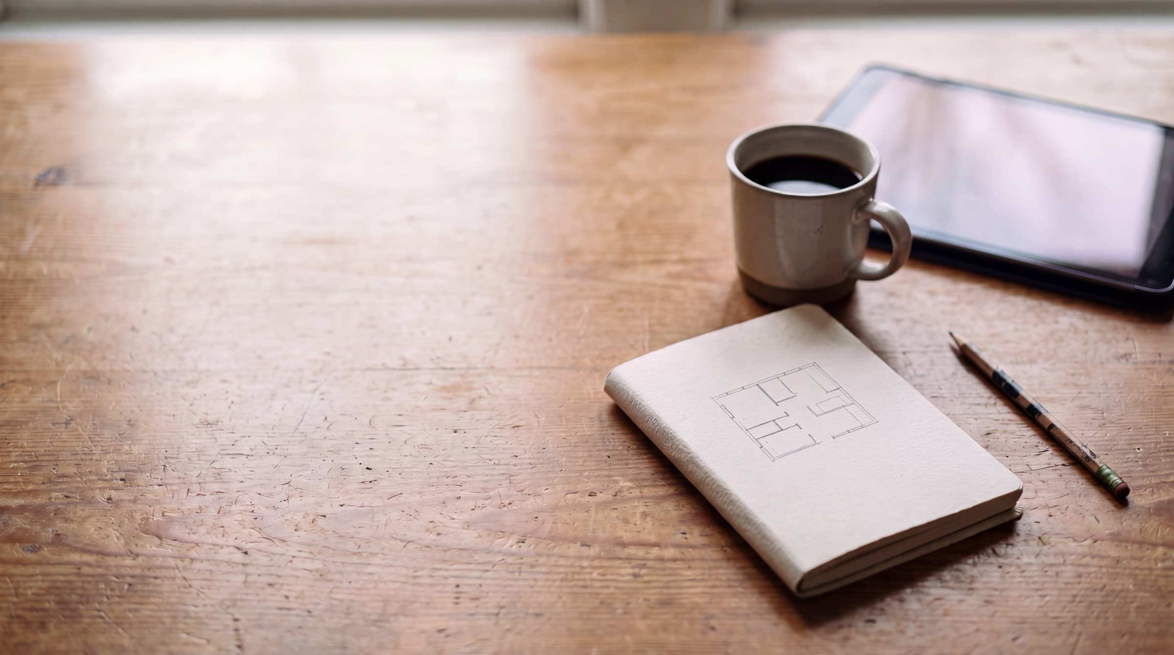 Bureau avec un carnet, un café et une tablette en lecture